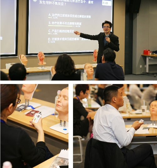 A person is presenting in a classroom with anatomical models on tables, while attendees listen and look at the materials in front of them.