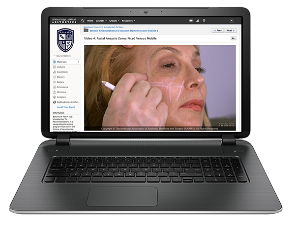 A laptop displaying a video titled "Video 6: Facial Analysis Zones Fixed vs. Mobile" from The American Association of Aesthetic Medicine and Surgery. The video shows a person being examined.